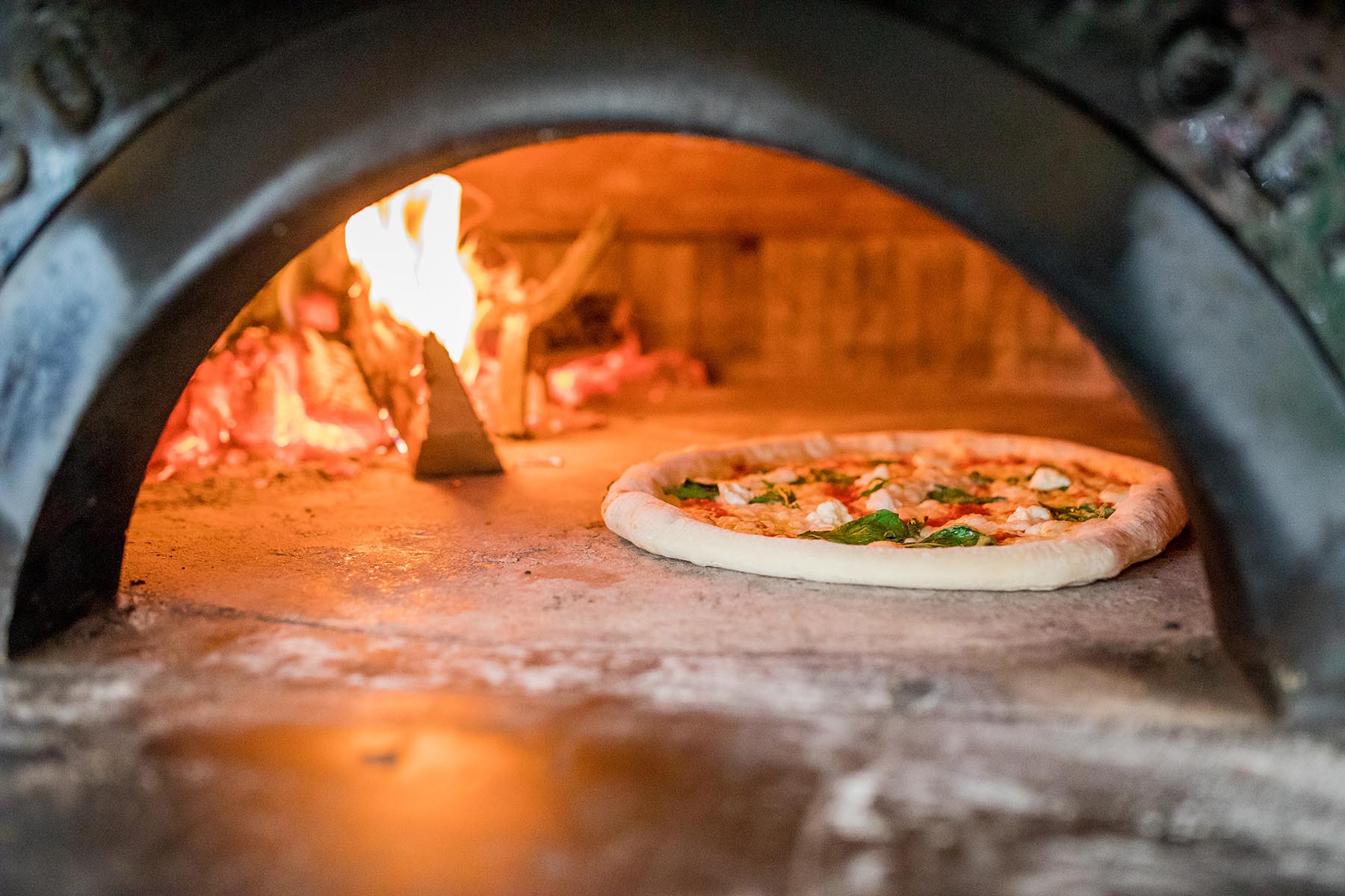An unbaked pizza sitting in a wood-fired oven at Cugino Forno.