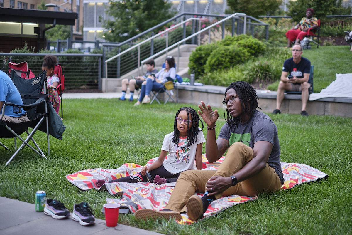 An adult and child discussing a movie showing in the Innovation Quarter's Bailey park, an example how placemaking can improve quality of life and engage the community.