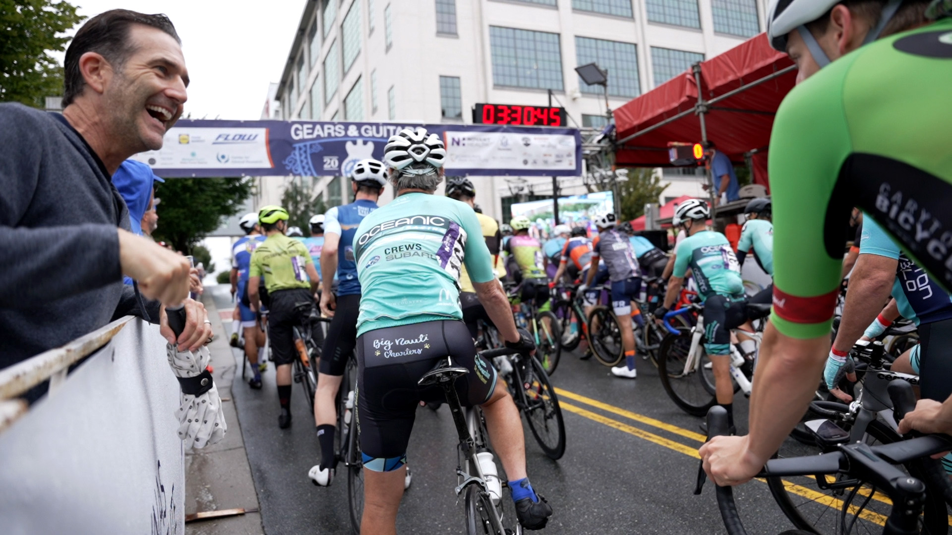 A spectator jokes with a cyclist at the starting line of a race during Winston-Salem's Gears and Guitars festival.