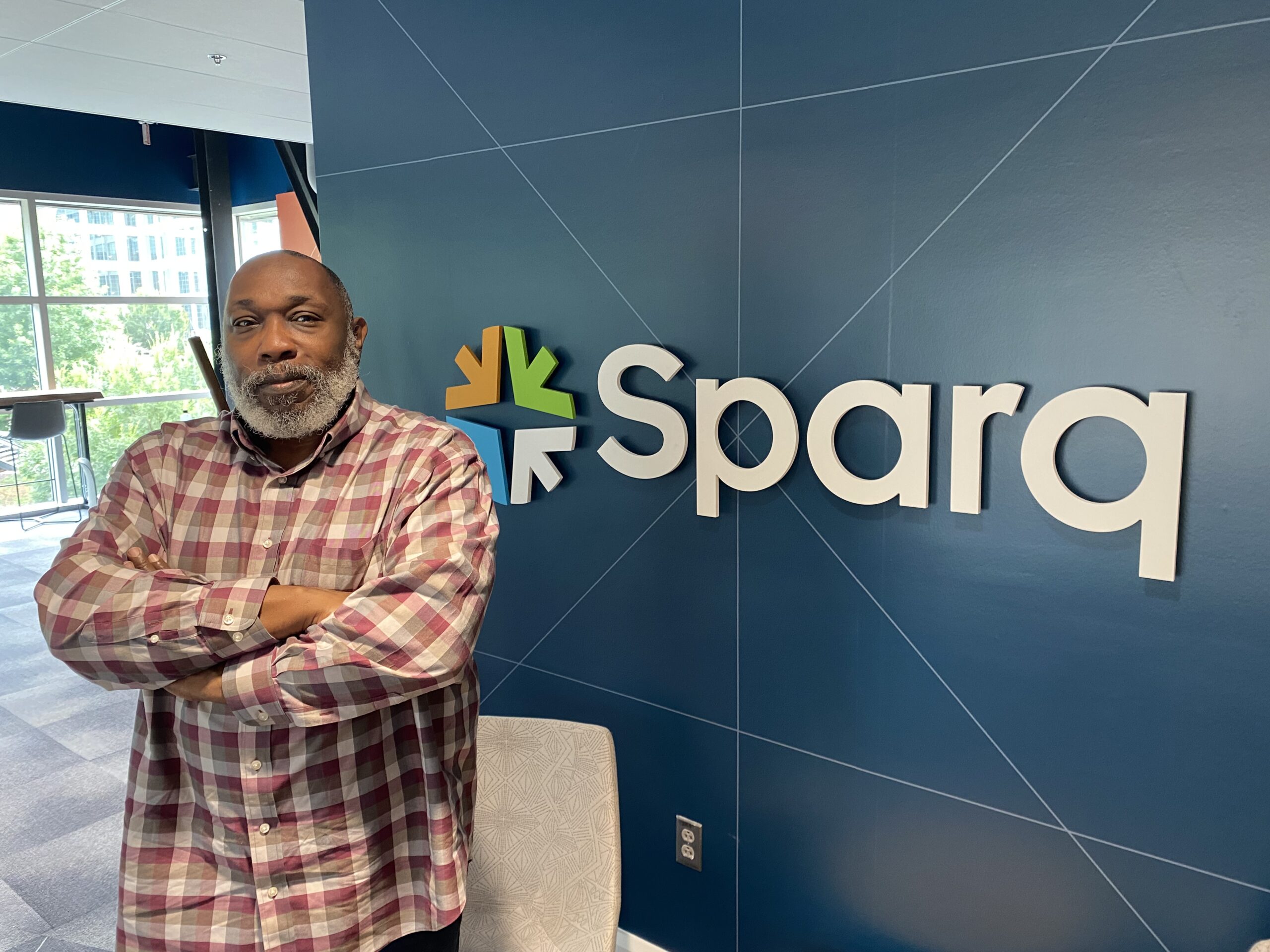 Ray Mitchell poses in front of SparqTM sign